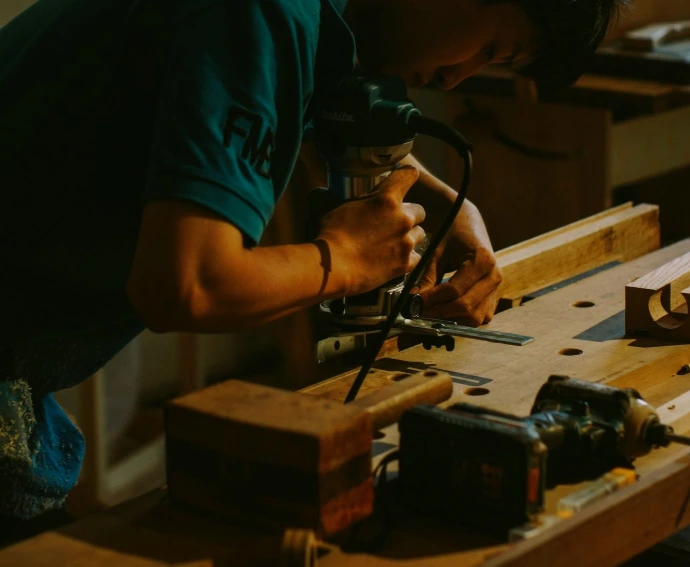 Carpenter using a router on wood in workshop